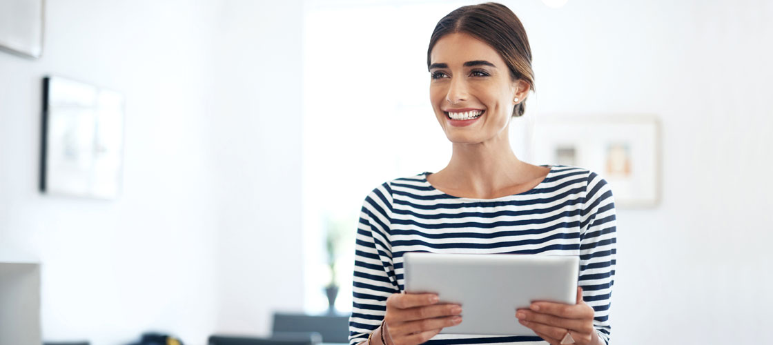 Smiling business woman holding a tablet in her office