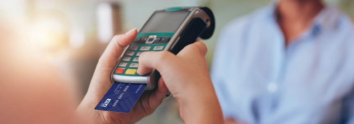 Hand holding a chip card reader with inserted debit credit card