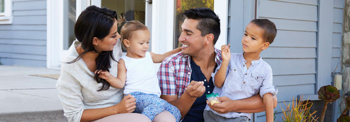 Happy family sitting in front of their home 