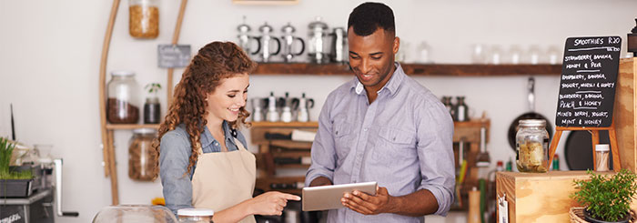 Small business owner and employee looking at tablet for financial education 